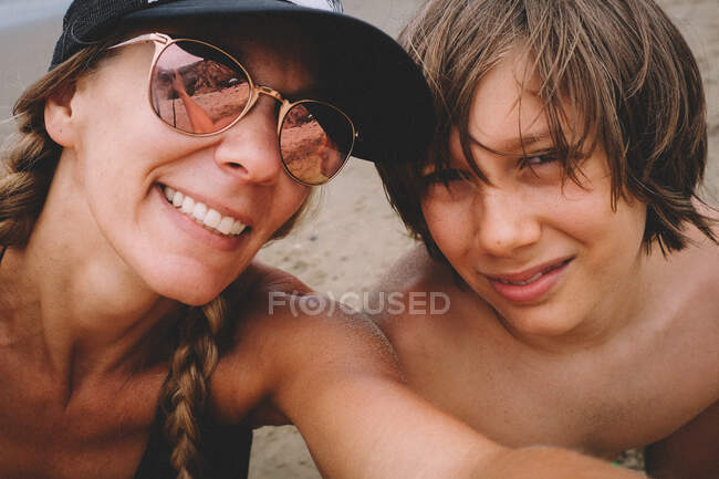 Madre e hijo posan para un selfie en la playa - foto de stock