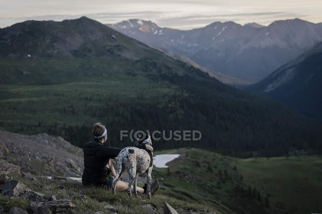 Mujer mirando montañas mientras camina con el perro durante las vacaciones - foto de stock