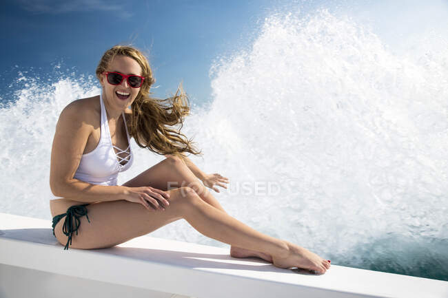 Jeune femme éclaboussée par la vague sur le bateau — Photo de stock