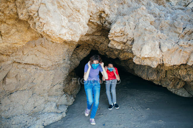 Adolescent fille et son frère mis sur visage masques tout en sortant un mer grotte — Photo de stock