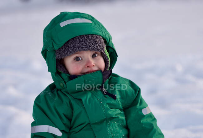 Portrait of smiling little boy playing in snow on cold winter day — Stock Photo