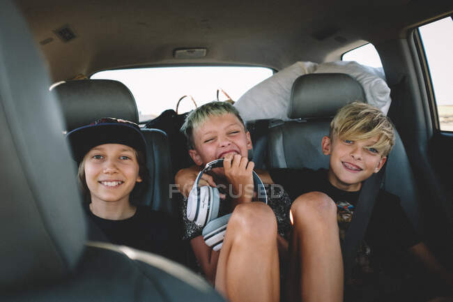 Tres mejores amigos en un viaje por carretera se ríen desde el asiento trasero - foto de stock