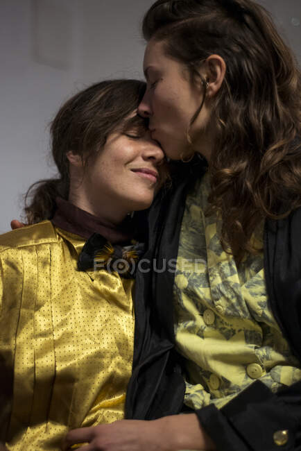 Tierno momento entre dos mujeres gay enamoradas en casa abrazándose - foto de stock
