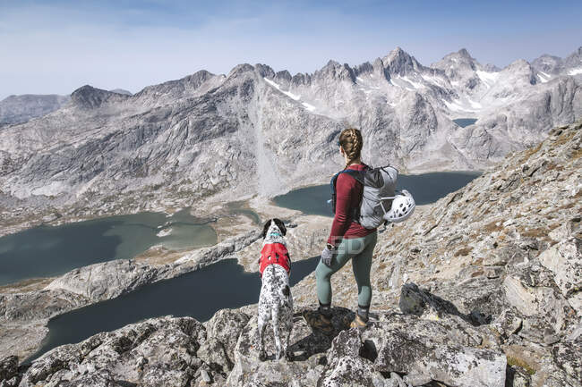 Young woman hiking with dog on mountain during vacation — Stock Photo