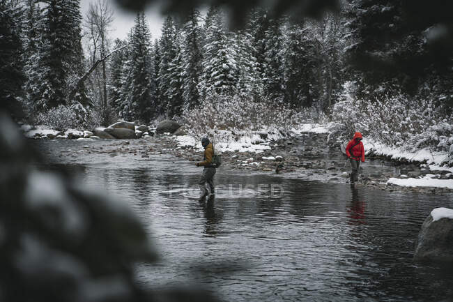 Uomo e donna a piedi nel fiume durante la pesca a mosca in inverno durante le vacanze — Foto stock