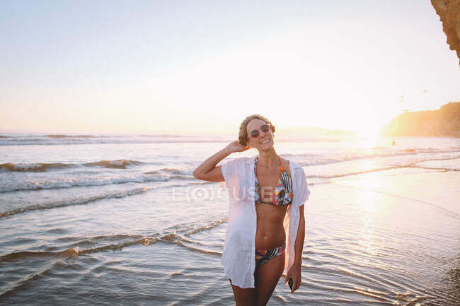 Жінка в тропічному бікіні на пляжі на заході сонця. — стокове фото