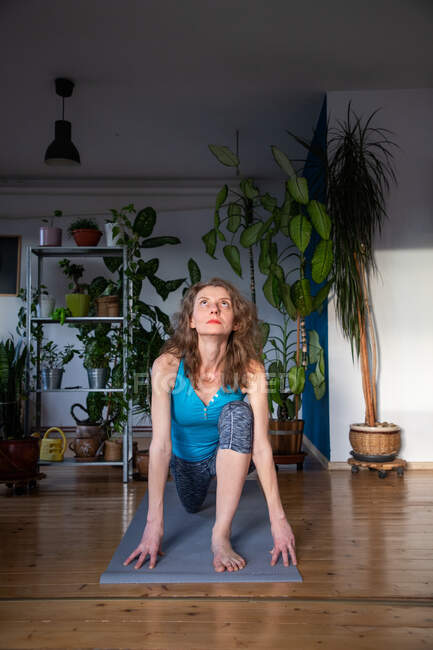 Donna che fa yoga a casa piante d'appartamento in background — Foto stock