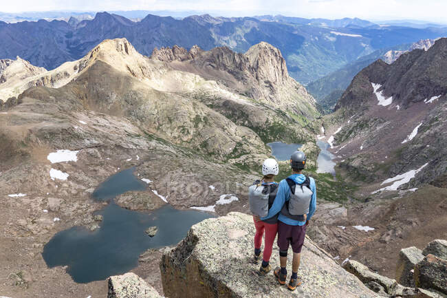 Visão traseira do casal olhando para a vista enquanto está em pé na montanha — Fotografia de Stock