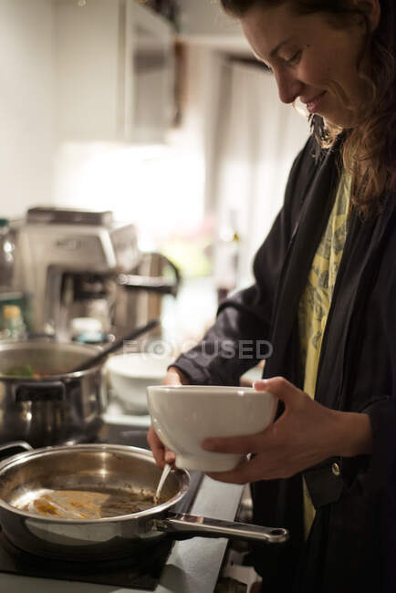 Femme heureuse sourit alors qu'elle sert un dîner sain à la maison en confinement — Photo de stock