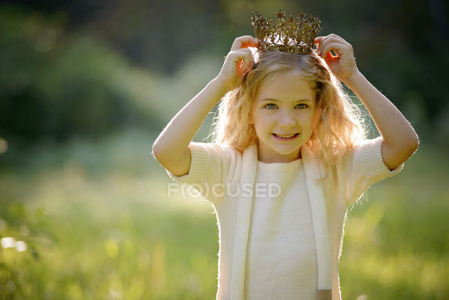 Красивая маленькая блондинка надевает корону на открытом воздухе. — БУФФАЛО, Беззаботная - Stock Photo