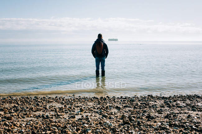 Людина стояла в океані думаючи, розмірковуючи і мріючи на сонці — стокове фото