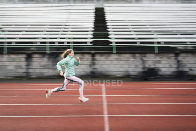 Side View of Determined Young Athletic Girl Running on Red Track — Stock Photo