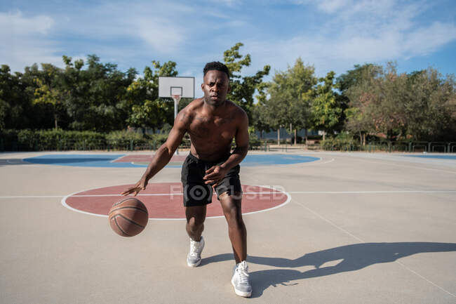 Strong African American man running and doing freestyle dribbling on court — Foto stock