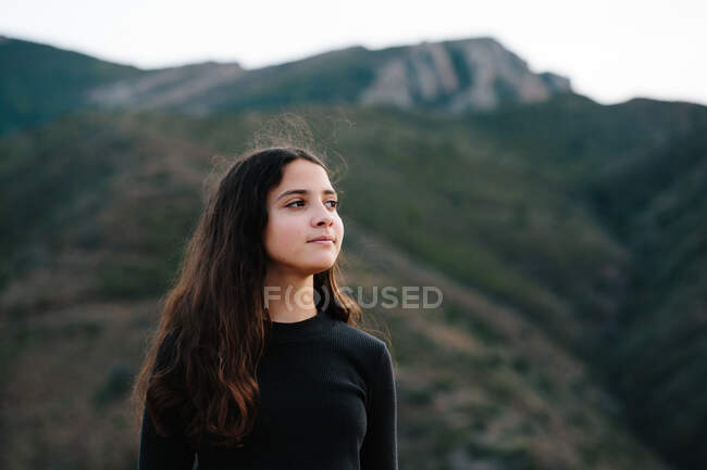 Tra ragazza in piedi fuori con montagna in il sfondo — Foto stock