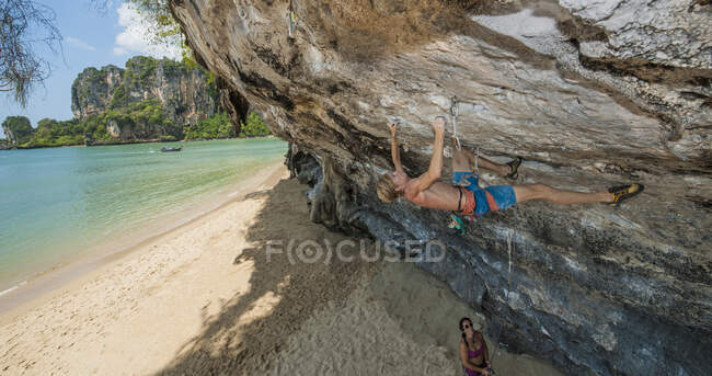 Jovem escalando rochas penduradas na praia de Tonsai — Fotografia de Stock