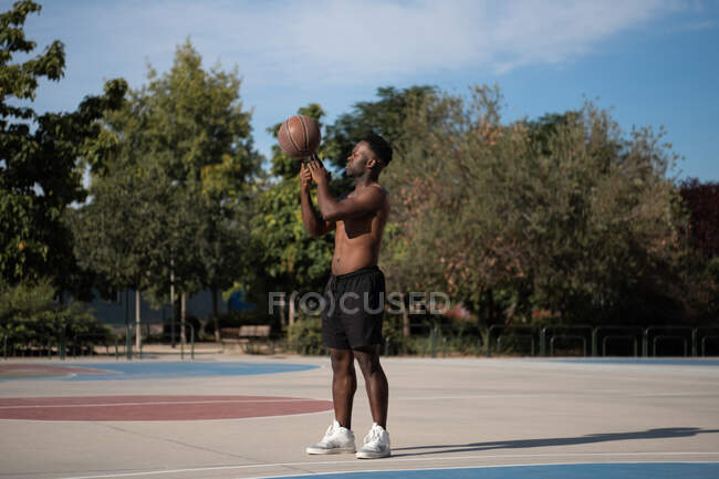 Joueur afro-américain fort faisant un tour avec une balle tout en jouant au basket — Photo de stock