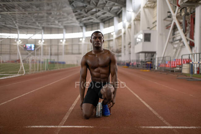 Sweaty African American athlete preparing to start run during training in stadium — Fotografia de Stock