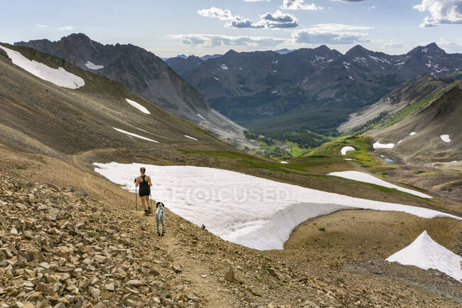 Visão traseira da mulher caminhando com o cão na montanha no inverno durante as férias — Fotografia de Stock