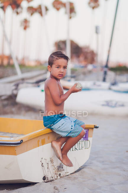 Lindo niño sentado en la playa - foto de stock