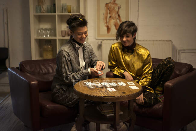 Amici giocare a carte a casa cena su poltrone e ridere — Foto stock