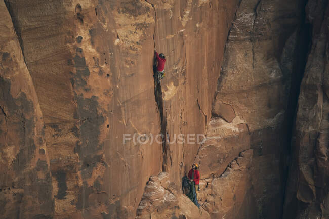 Мужчины, карабкающиеся по скалистой скале в Национальном парке Каньонлендс — стоковое фото
