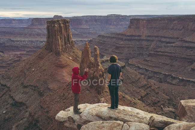 Amigos do sexo masculino em pé na borda do pico no Canyonlands National Park — Fotografia de Stock