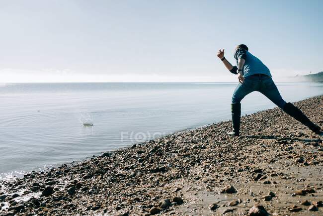 Mann beim Abschöpfen eines Steins im Ozean an einem sonnigen Tag in Großbritannien — Stockfoto