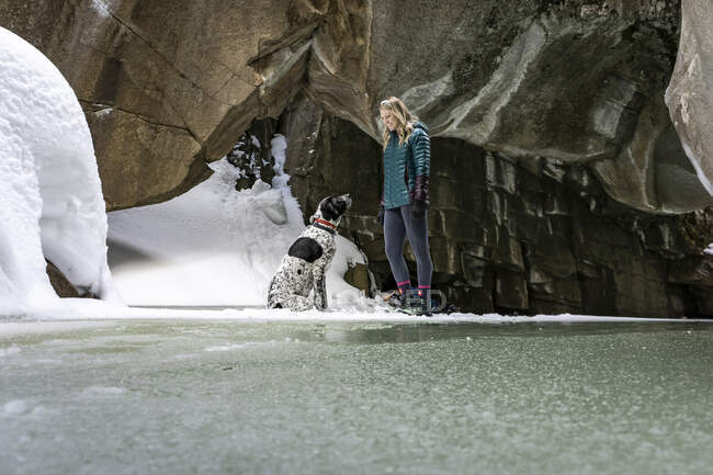 Улыбающаяся молодая женщина с собакой в пещере зимой — стоковое фото