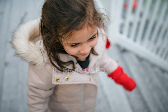 Junges glückliches Mädchen draußen in Wintermantel und Fäustlingen — Stockfoto