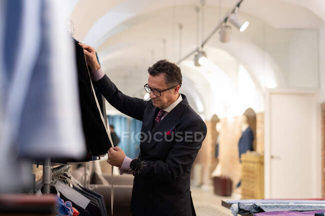 Uomo maturo in abito misura giacca elegante su rotaia durante il lavoro in studio sarto — Foto stock