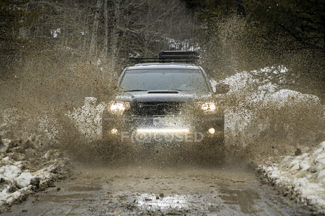 Caminhão dirigindo através da lama na primavera — Fotografia de Stock