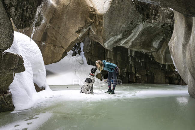 Junge Frau küsst Hund im Winter in Höhle — Stockfoto