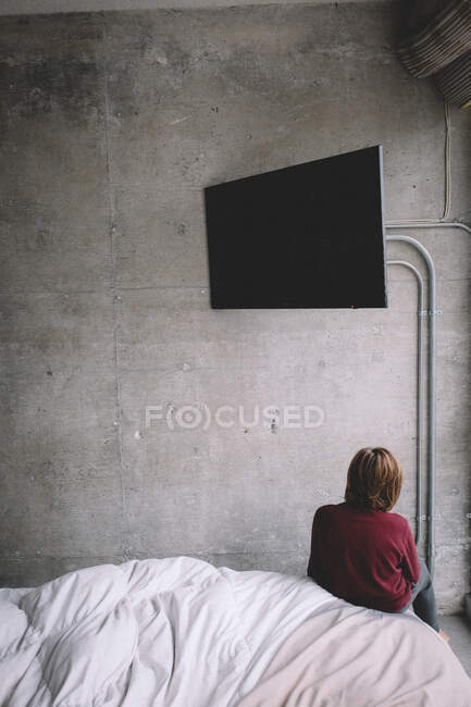 Menino enfrenta parede de concreto com TV em branco pairando sobre sua cabeça. — Fotografia de Stock