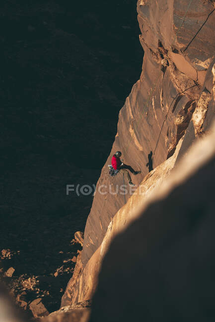 Vista de alto ángulo del hombre escalando un acantilado rocoso en el Parque Nacional Canyonlands - foto de stock