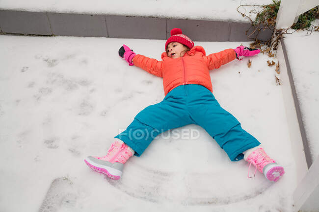 Giovane ragazza che fa angeli di neve in fredda giornata invernale — Foto stock