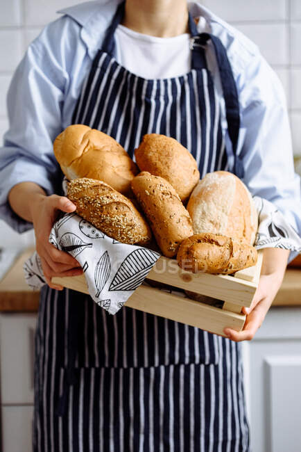 Jovencita sosteniendo pan en la cocina - foto de stock