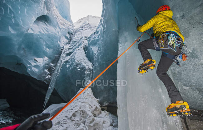 Hombre escalada carámbano dentro de glaciar cueva en Islandia - foto de stock