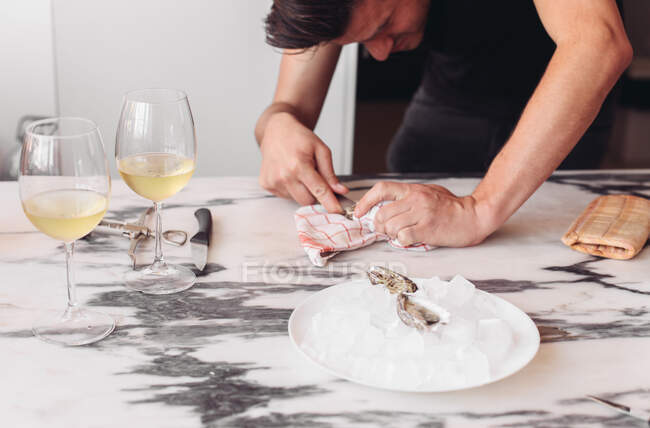 Un homme ouvrant une huître, deux verres de vin blanc, rendez-vous romantique — Photo de stock