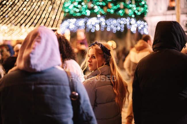 Giovane donna a piedi sulla piazza della città durante la notte di Natale — Foto stock