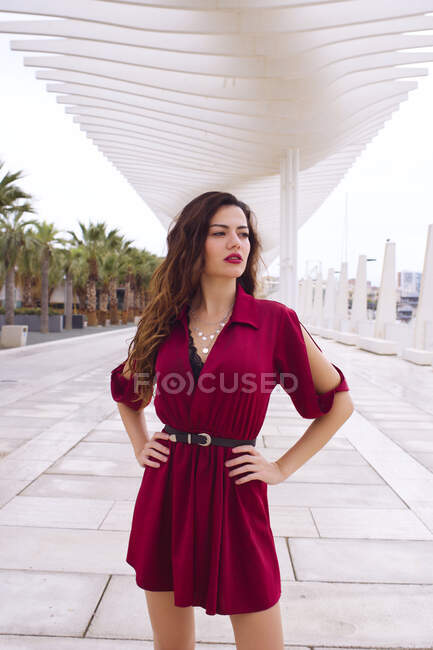 Attrayant et joli mannequin pose avec robe rouge sur une rue de la ville — Photo de stock