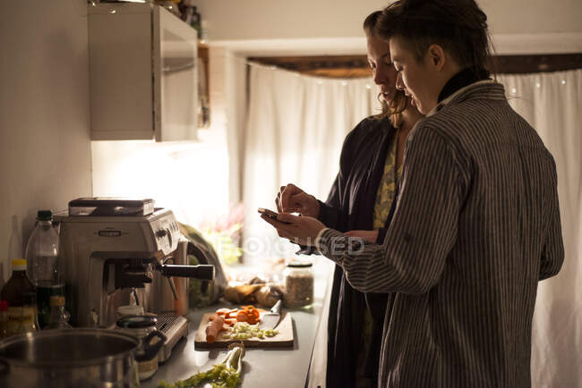 Gay couple suivre téléphone recette dans cuisine cuisson sain dîner — Photo de stock