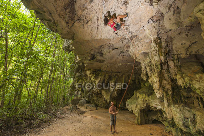Woman climbing overhanging rock face in the forest at Railay beach — Stock Photo