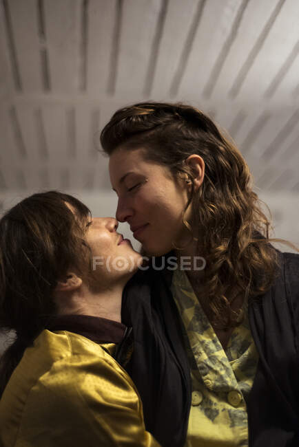 Queeriges Paar lächelt und sieht sich nachts zu Hause liebevoll an — Stockfoto