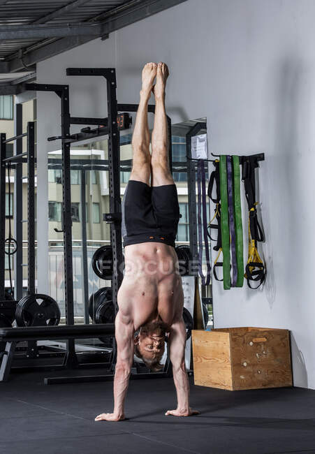 Man with beard performing handstand at gym — Stock Photo