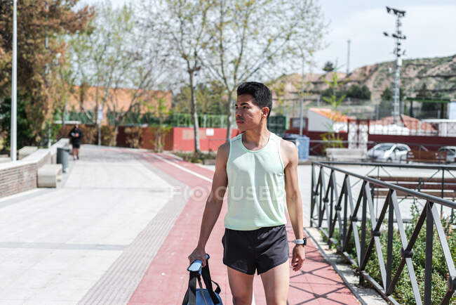 Atleta sudamericano che cammina con la sua borsa sportiva in città. Concetto in esecuzione. — Foto stock