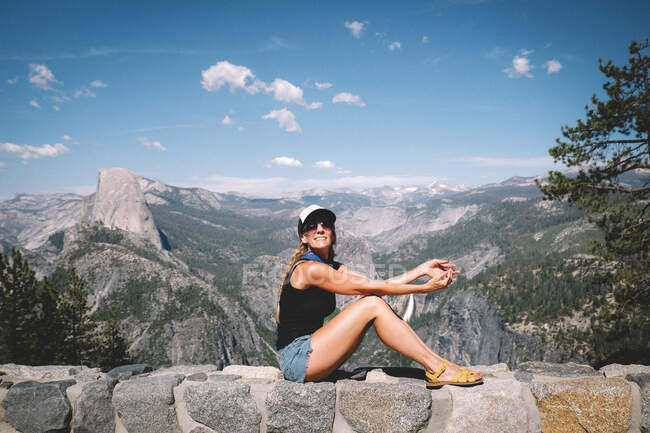 Женщина позирует для фото на стене над долиной Йосемити — стоковое фото