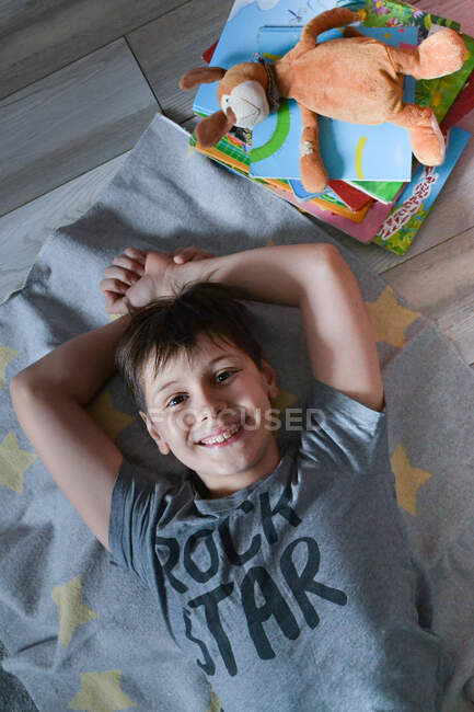 Gros plan garçon se trouve sur le sol à côté des livres — Photo de stock