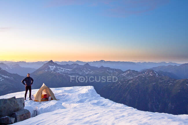 Scalatore in piedi accanto alla tenda in cima alla montagna, Whistler, Canada. — Foto stock