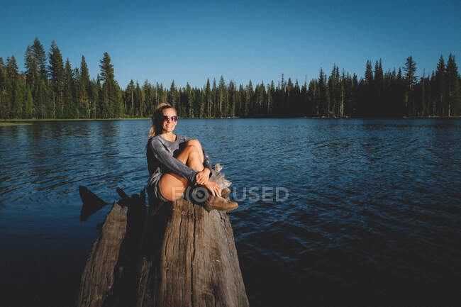 Mujer con gafas de sol sonriendo cerca de un hermoso lago de Sierra Alta - foto de stock