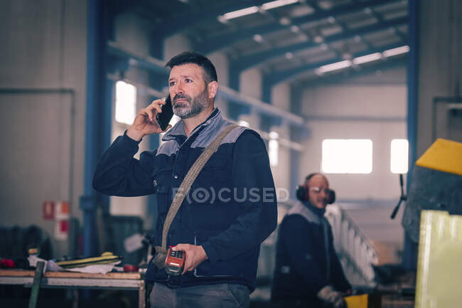 Man talking by telephone with the control of a bridge crane — Stock Photo